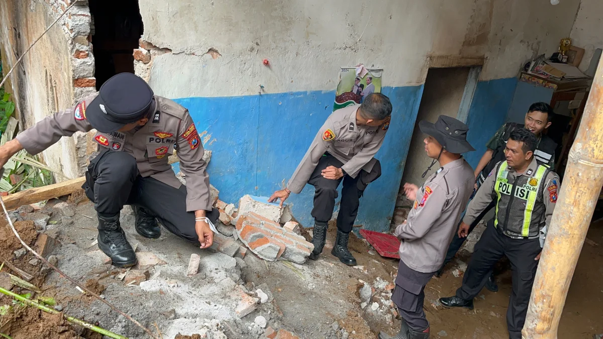 Personel Sat Samapta Polres Lumajang bersama anggota Polsek Pronojiwo membantu membersihkan material tanah longsor yang menimpa rumah warga di Desa Tamanayu, Kecamatan Pronojiwo, Kabupaten Lumajang, Sabtu (31/10/2026).